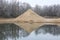 Lake with artificial sand dune and forest in background