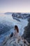 Lake Baikal at winter. Woman sitting on a edge of cliff and looking at frozen Baikal lake.