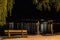 Lake beach bench by sidewalk at night illuminated with street lantern. Zell am see Austria