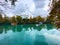 On the lake, a catamaran and boat against the background of houses and trees. Autumn