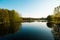 A lake in the city park early in the morning. Quiet and peaceful, in harmony, no people. Fresh green trees and grass, blue sky and