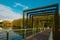 A lake in the city park. Quiet and peaceful, in harmony. Lonely fisherman on a modern metal geometric bridge. Fresh green trees