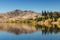 Lake in the dry landscape with trees and mountains. Horizontal image with reflections in the water. Beautiful background