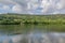 Lake Echternach with its calm water, hills with abundant leafy trees in the misty background