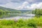 Lake Echternach landscape with fishing platform on shore, calm water, hills with abundant leafy trees