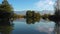 Lake at the edge of the mountains with forest reflected in the clear water. Idyllic autumn landscape. The forest and the sky in th