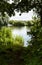 Lake framed by trees on a shady bank