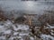 Lake with frozen surface and hole in ice with visible signs of beaver with tree trunks with beaver damage, wood chips