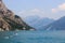 Lake Garda and mountain panorama with boat and relaxing people on airbed in Limone