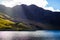 Lake with a hill and mountain at the background and sunrays crossing through the cloudy sky, in Snowdonia National Park, Wales