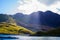 Lake with a hill and mountain at the background and sunrays crossing through the cloudy sky, in Snowdonia National Park, Wales