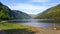 Lake in irish mountains with blue sky and forest in background.