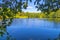 A lake in the middle of a green forest with red buoys in the water under the clear sky