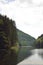 Lake mirroring rocky mountains with forest fir trees on summer season