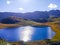 Lake with mountains at the background and sunrays crossing through the cloudy sky and reflected in the water. Snowdonia National