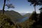 Lake and mountains between forest with snowy volcano.