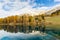 Lake Palpuogna with yellow larch trees and reflection in autumn season