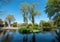 The lake at Pinner Memorial Park, Pinner, Middlesex, UK, photographed on a sunny spring day. The trees are reflected in the water.