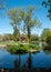 The lake at Pinner Memorial Park, Pinner, Middlesex, UK, photographed on a sunny spring day. The trees are reflected in the water.