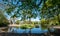 The lake at Pinner Memorial Park, Pinner, Middlesex, UK, photographed on a sunny spring day. The trees are reflected in the water.