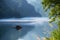 Lake with reflections and a small boat with foggy mountains on the background