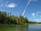 Lake shines green in summer under blowing clouds, white clouds of interesting shape reflect on lake surface