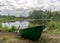 Lake shore and boat, calm lake water surface, tree reflections, cloudy day, fishing concept