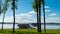 Lake shore scene in summer, with trees, boats, blue sky and white clouds