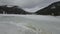 Lake Spitzingsee in winter covered with snow and ice in freezing cloudy weather in Bavaria, Germany. A mountain lake in