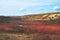 Lake in a sunny picturesque autumn hilly valley, against a background of a clear blue sky with sparse clouds. Day`s landscape