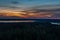 A lake surrounded by forest expanses after sunset