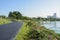 Lakeside blacktopped pedestrian path on grassy lawn in sunny summer morning