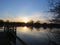 Lakeside jetty and setting sun with silhouette trees