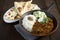 Lamb curry accompanied by fragrant basmati rice, warm naan bread, and a refreshing side of cucumber raita. Generative AI