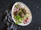 Lamb kebab on flatbread with lettuce, onions and pomegranate. On a dark background