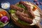 Lamb kebabs on serving board with pita bread, vegetables and yogurt sauce.