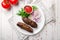 Lamb Lula kebab with greens and sliced red onion and tomato sause on white wooden table