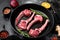 Lamb rib cuts cutlet, on frying cast iron pan, on black dark stone table background