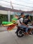 Lamongan, East Java, Indonesia. a motorcyclist carrying a kite in the shape of a green dragon\'s head