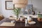 Lamp above wooden table with food and bowls in grey dining room interior with posters. Real photo