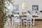 Lamp above wooden table in rustic dining room interior with white chairs and posters. Real photo