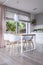 Lamp above wooden table and white chairs in dining room interior with drapes and window. Real photo