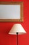 Lamp and framed mirror on red stylish wall