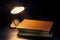 Lamp lighting books on a wooden table. Retro style bedroom interior