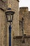 A lamp stands out in gold and blue splendor against dull stonework of medieval fortifications.
