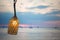 The lamp on the wire tied with a rope. On the background of the beach. Inside the light bulb shines, evening