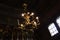 Lamps in the form of candles light on chandelier in ancient wooden Orthodox church