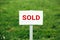 Land sold plate sign, green grass background