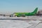 Landed green passenger airplane with attached ladder in winter airport