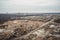 landfill with towering pile of trash, surrounded by landscape of industrial buildings